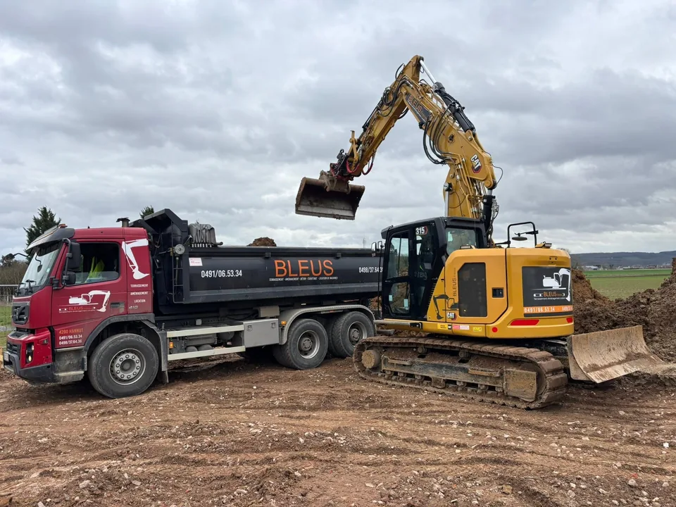 Pelle jaune et camion benne BLEUS au chargement des terres sur le chantier