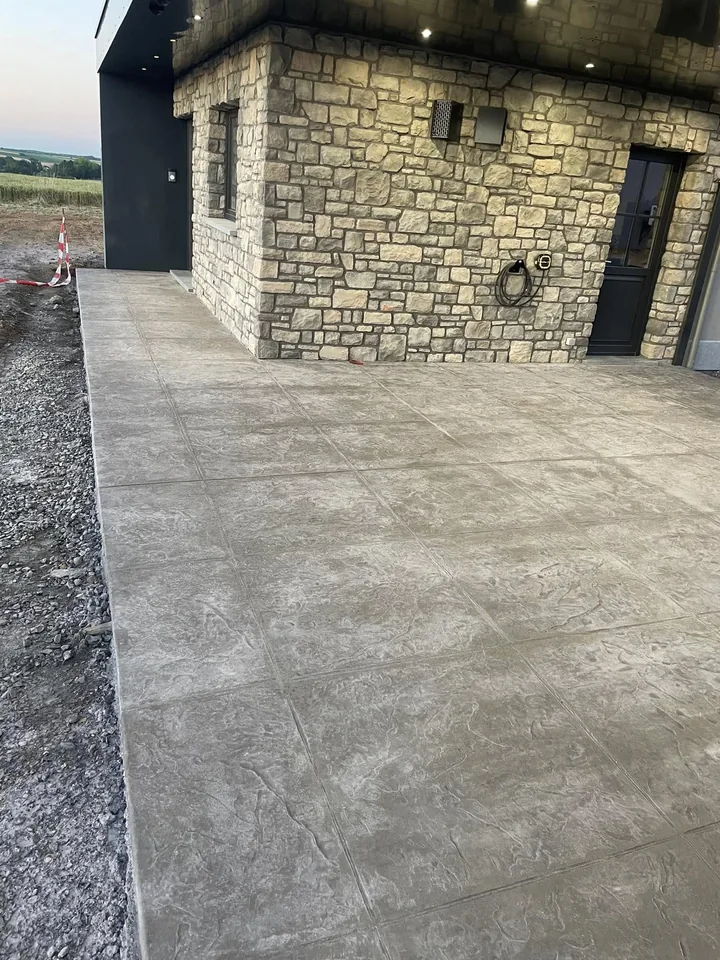 Dalle de béton imprimé le long d'un mur en pierre