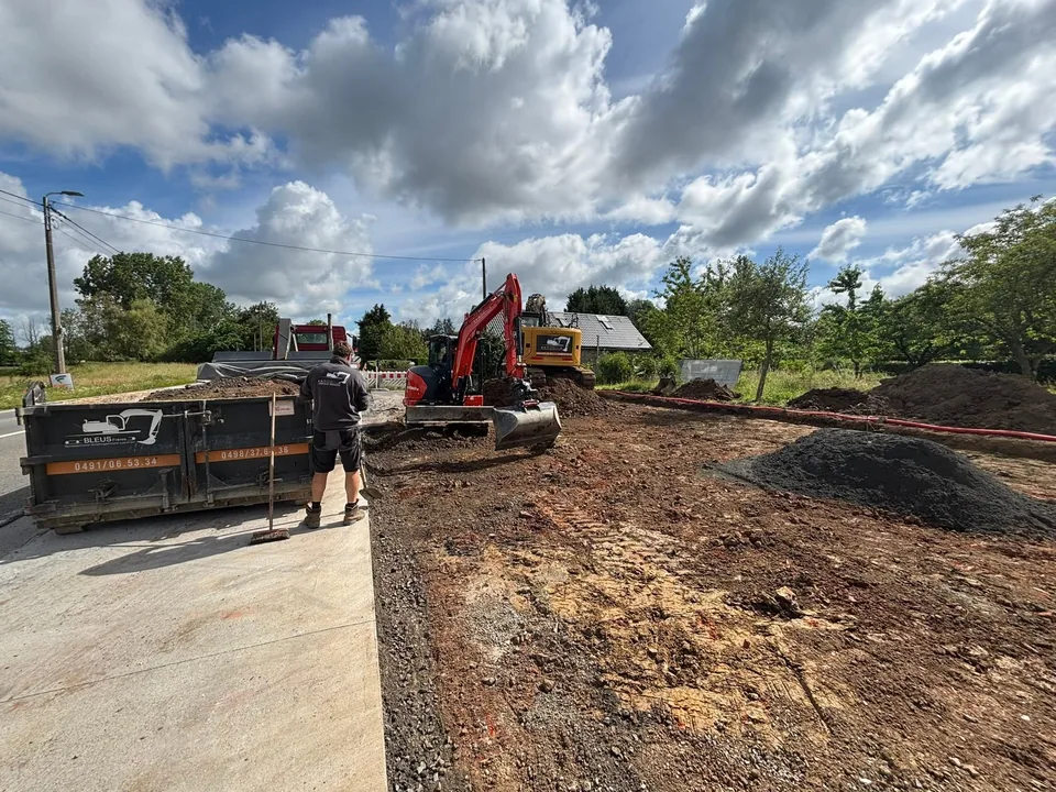 Chantier en cours : bordures posées, benne de chantier et mini-pelle au fond