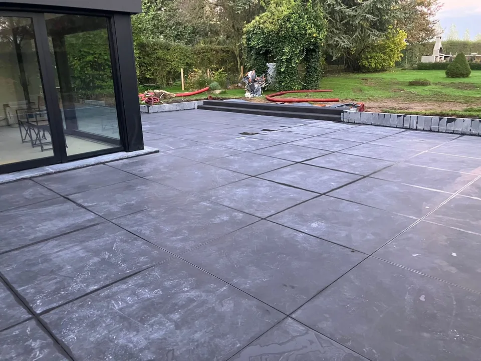 Terrasse en béton foncé avec sciage effet carrelage devant la baie vitrée