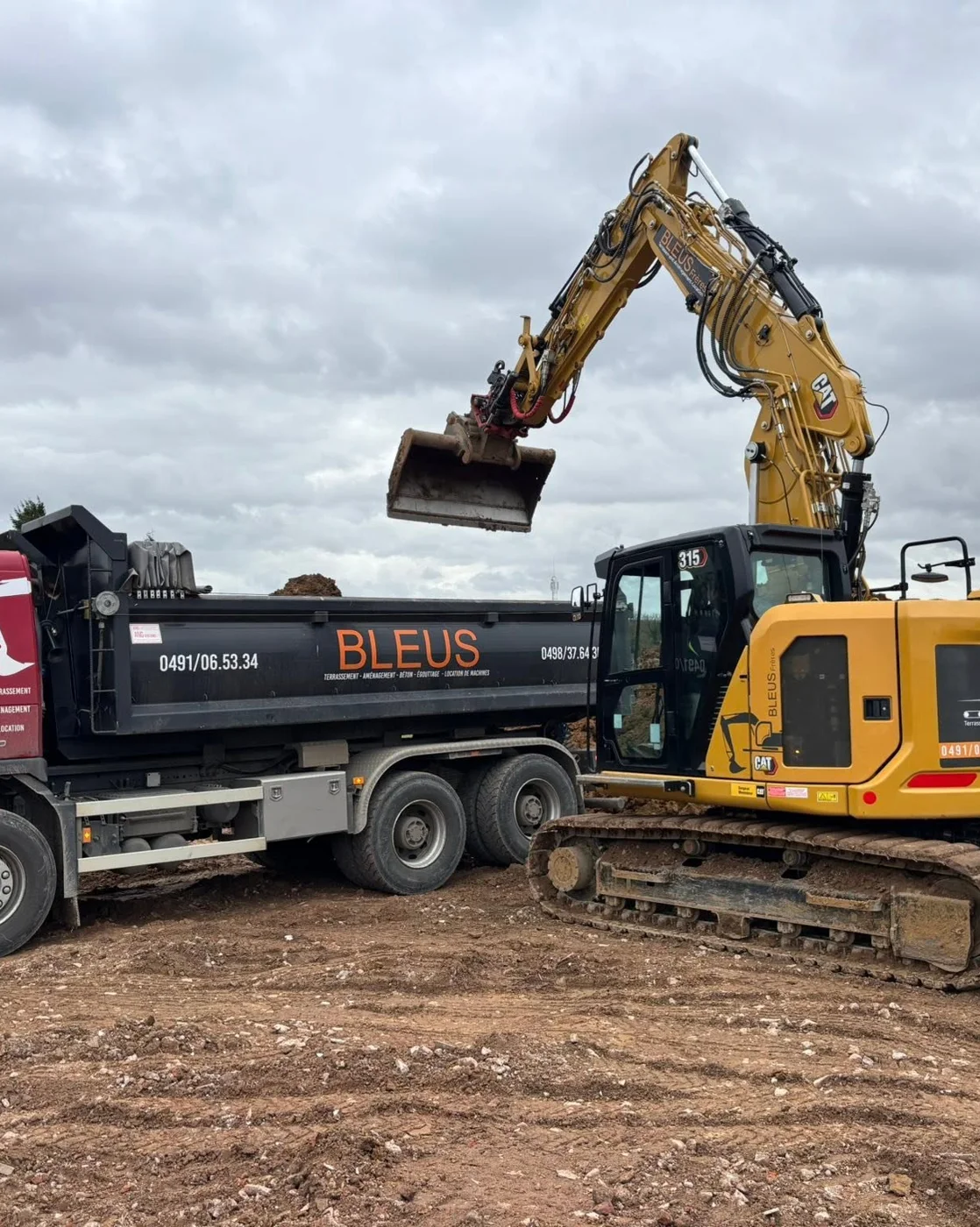 Camion benne BLEUS et pelle CAT sur un terrain